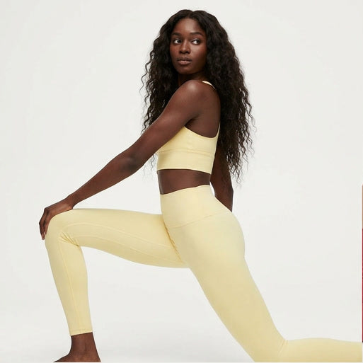 Four women in different colored athletic wear posing against a white background