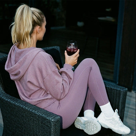 Woman in a lavender loungewear set sitting and posing outdoors.