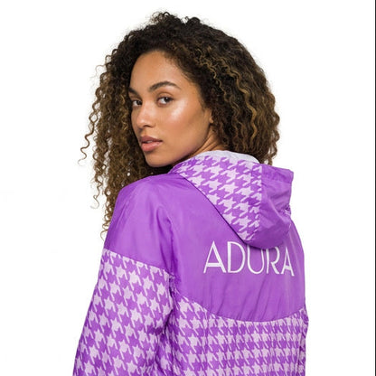 Purple and white checkered hoodie with 'Adura' branding worn by a model on a white background
