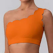 Person wearing an orange sports outfit with leggings and a crop top on a gray background